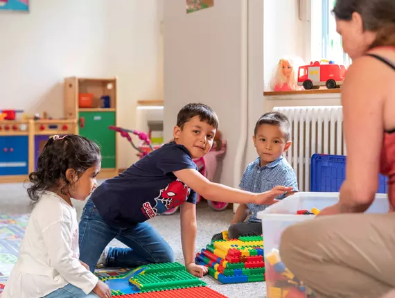 Enfants qui jouent – un projet de HEKS Des enfants jouent par terre en riant – image issue d’un projet de l’ONG HEKS.