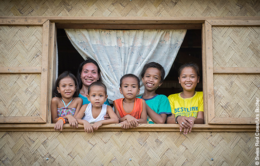 aux Philippines, une famille regarde par la fenêtre de sa nouvelle maison.